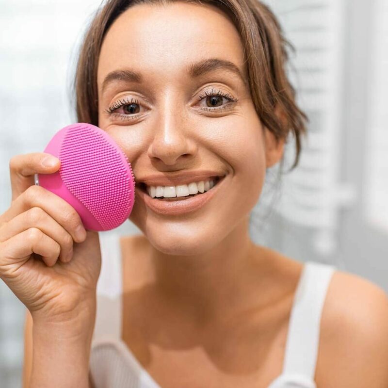 Jeune femme se nettoyant le visage avec la brosse massante Splendia