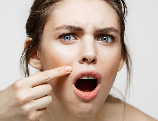 Femme pointant de l'index une imperfection sur son visage