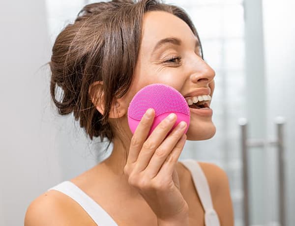 Jeune femme senttoyant le visage avec la brosse rose Splendia